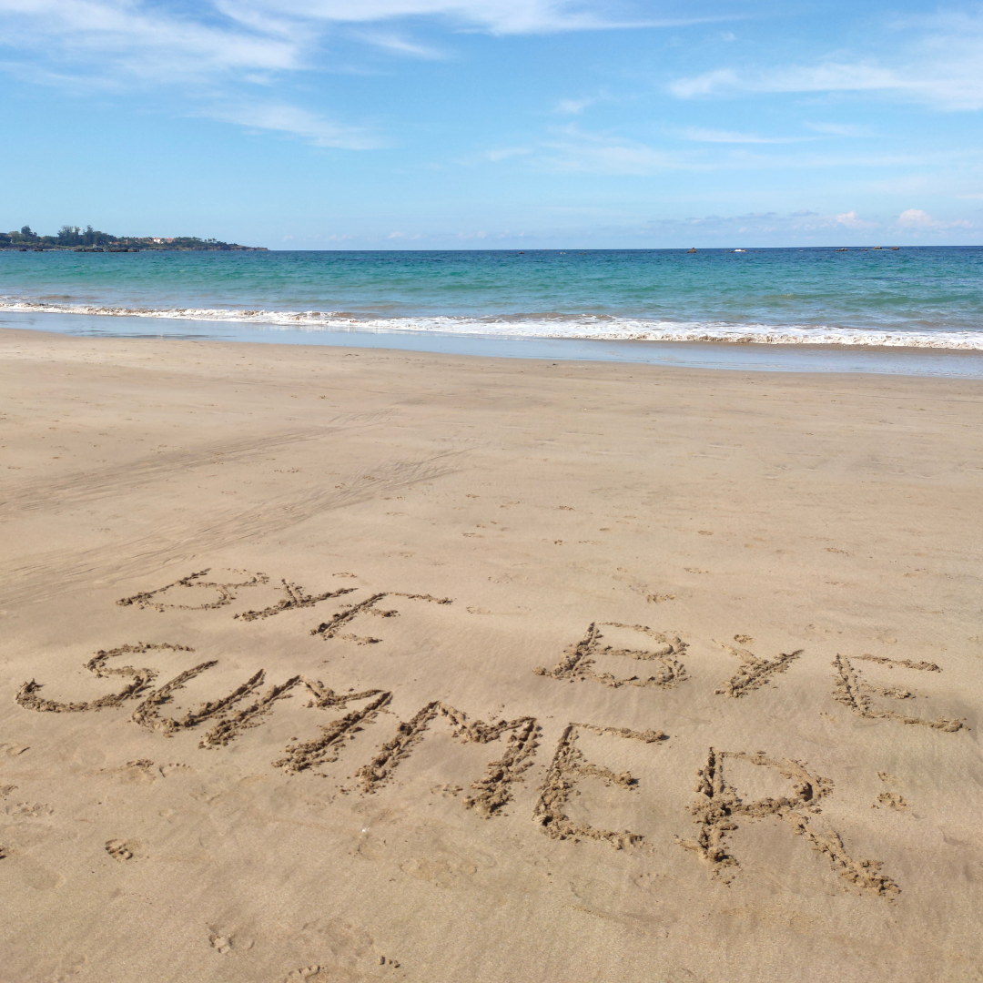 Beach scene with writing in the sand that says 'Bye bye' summer